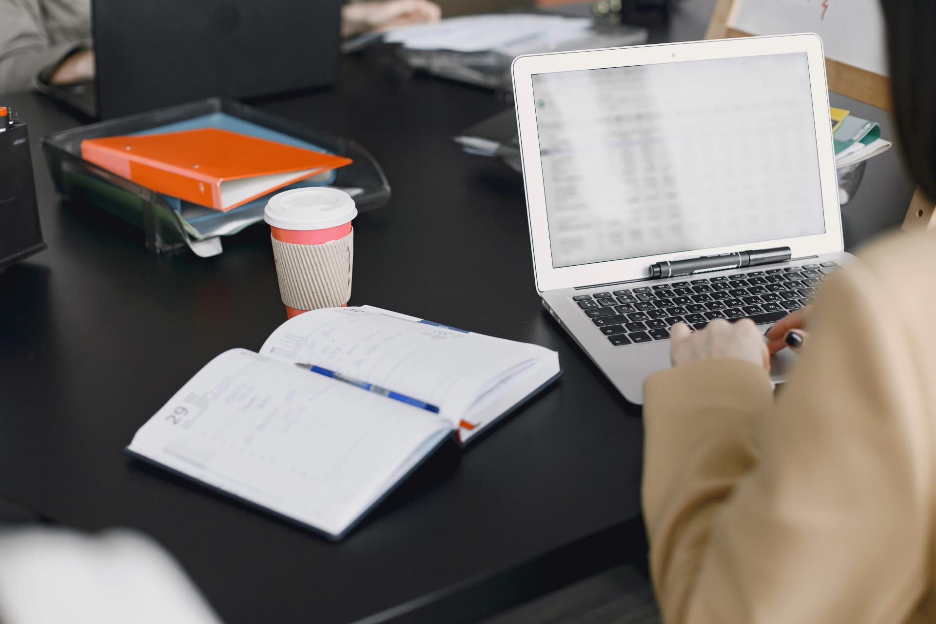 Author working on a laptop with notebook and coffee at a desk