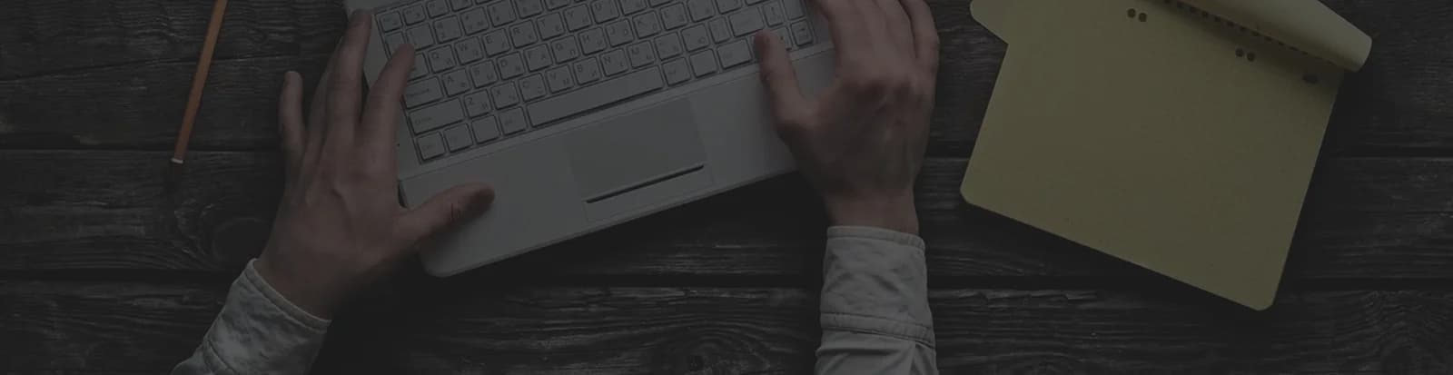 Hands typing on a laptop at a desk